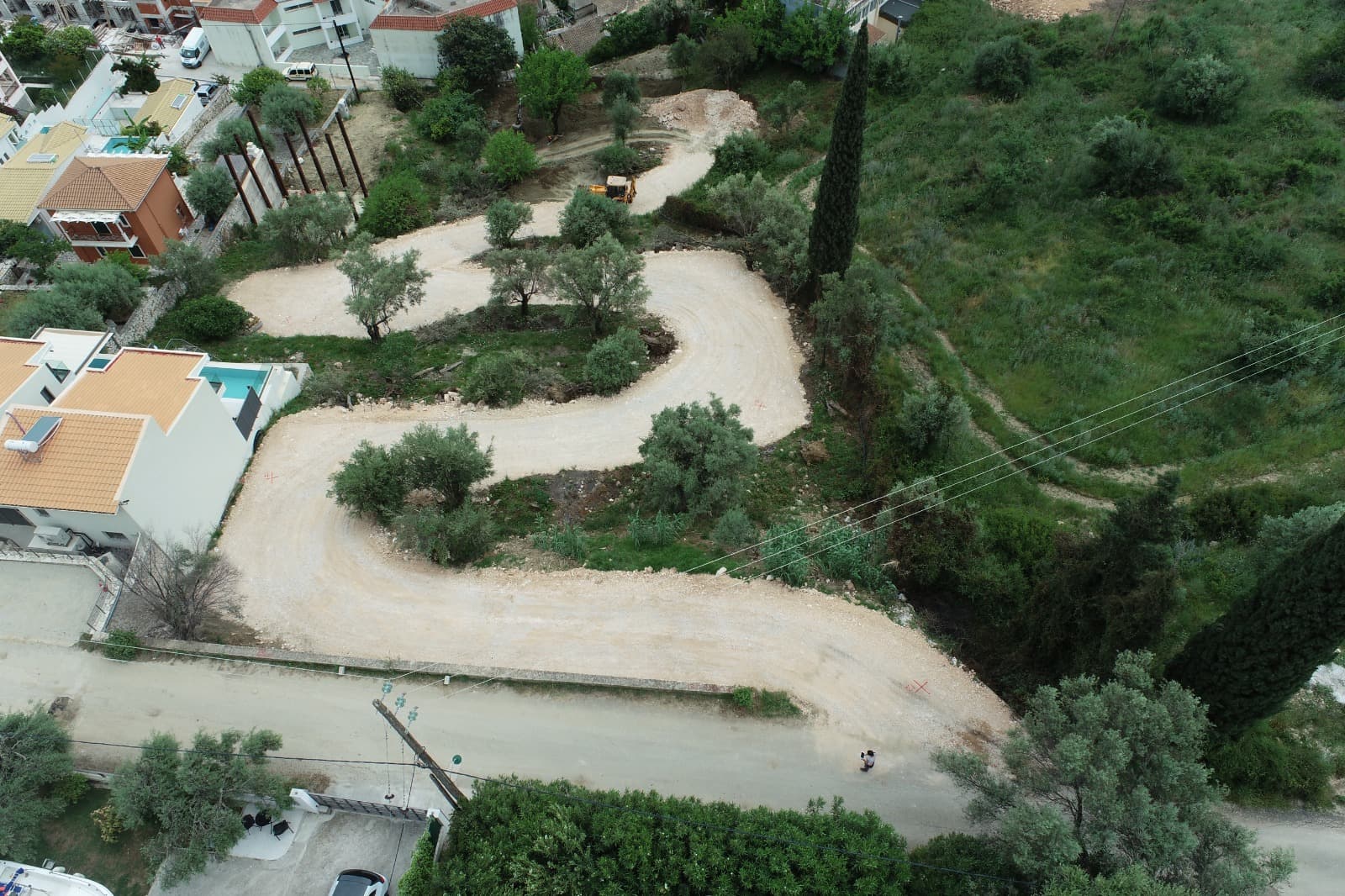 Aerial view of the site with the new access road cut through the olive terraces.